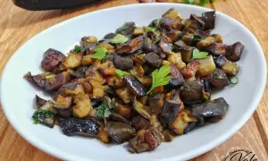 Un piatto invitante di melanzane al funghetto, tagliate a cubetti e saltate con erbe aromatiche, guarnito con prezzemolo fresco.