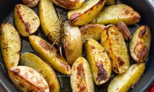 Patate con la buccia dorate al forno, condite con rosmarino e aglio. Un contorno rustico e saporito.