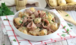 Un gustoso piatto di totani e patate, condito con prezzemolo fresco, pronto per essere gustato.