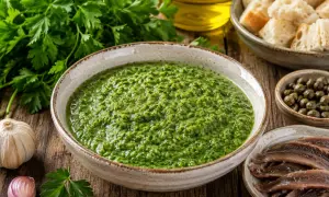 Una ciotola di vibrante salsa verde, con aglio, prezzemolo, capperi e acciughe, pronta per essere gustata.