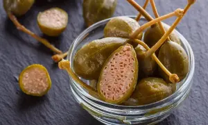 Cucunci sotto sale in una ciotola di vetro. Uno è tagliato a metà, mostrando la sua polpa interna.