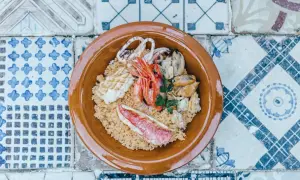 Un invitante cous cous di pesce con gamberi, calamari, cozze e pesce rosso, guarnito con prezzemolo fresco.