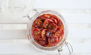 Barattolo di vetro pieno di succulenti pomodorini confit, pronti per insaporire ogni piatto.