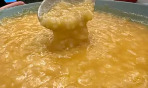 Un mestolo solleva una porzione cremosa di riso e patate, un comfort food dorato e invitante.