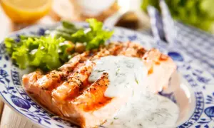 Salmone grigliato con salsa vierge e insalata fresca, un piatto leggero e gustoso.