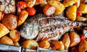 Orata alla ligure al forno, con patate arrosto, pomodorini e aglio. Un piatto succulento e profumato.