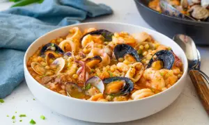 Un invitante piatto di fregola sarda con frutti di mare freschi: cozze, vongole, gamberi e calamari, condito con erbe aromatiche.