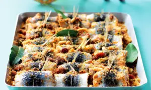 Sardine ricette: gustose sardine al forno con pangrattato, pinoli e pomodorini, pronte per essere gustate.