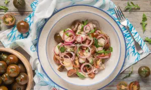 Rana pescatrice alla catalana: un'insalata fresca con pomodorini scuri, cipolla rossa e pesce bianco.