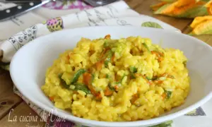 Un invitante risotto ai fiori di zucca cremoso, con petali arancioni e verdi che si mescolano al riso giallo dorato.