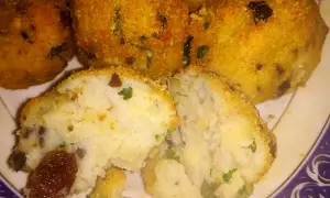 Polpette di merluzzo dorate e croccanti, una metà tagliata rivela un interno morbido con erbe aromatiche e pezzetti scuri.