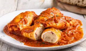 Calamari ripieni in padella, succulenti e ricoperti da un sugo rosso, pronti per essere gustati.