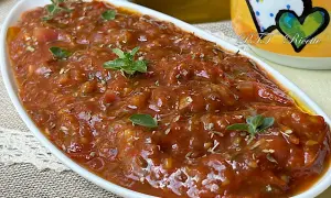 Sugo con pomodorini freschi, profumato con erbe aromatiche, servito in una ciotola bianca.