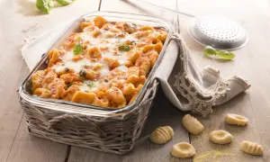 Gnocchi di polenta al forno, dorati e filanti, con basilico fresco. Un piatto invitante pronto per essere gustato.