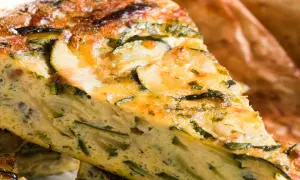 Fetta di torta salata con pasta sfoglia e zucchine, dorata e invitante, con verdure ben visibili nell'impasto.