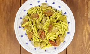 Un piatto di pasta alla carlofortina con trofie condite con pesto, pomodorini secchi e cubetti di tonno.