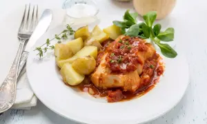 Un succulento merluzzo bollito in salsa di pomodoro, accompagnato da patate novelle e un rametto di timo.