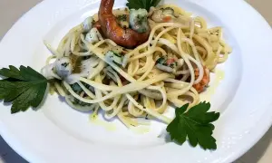 Un piatto invitante di pasta con mazzancolle, condita con erbe fresche e un filo d'olio.