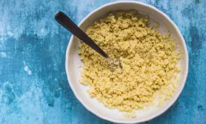 Ciotola di cous cous pronto per essere condito, con una forchetta che affonda nei granelli dorati.