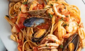 Un piatto invitante di scialatielli allo scoglio, con gamberi, cozze, vongole e calamari in un sugo rosso.