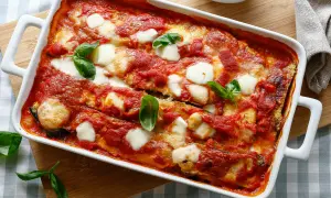 Parmigiana di zucchine, un classico delle ricette della nonna, cotta al forno con pomodoro e mozzarella filante, guarnita con basilico fresco.