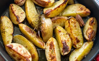 Patate con la buccia dorate al forno, condite con rosmarino e aglio. Un contorno rustico e saporito.
