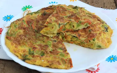 Frittata con fiori di zucca, carote e olive, tagliata a spicchi su un piatto bianco, con un tovagliolo colorato sullo sfondo.