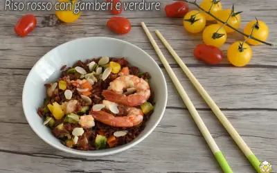 Un piatto di riso rosso con gamberi e verdure, un'idea per ricette veloci e gustose. Mandorle a lamelle completano il tutto.