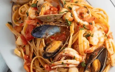 Un piatto invitante di scialatielli allo scoglio, con gamberi, cozze, vongole e calamari in un sugo rosso.