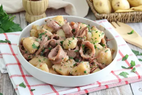 Un gustoso piatto di totani e patate, condito con prezzemolo fresco, pronto per essere gustato.