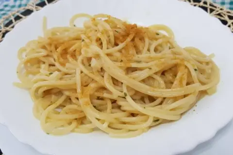 Spaghetti conditi con un filo d'olio, aglio e prezzemolo, spolverati con la preziosa bottarga.