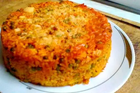 Timballo di riso dorato e invitante, con piselli e una crosticina croccante, pronto per essere gustato.
