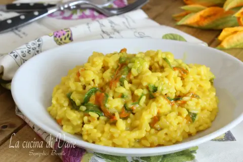 Un invitante risotto ai fiori di zucca cremoso, con petali arancioni e verdi che si mescolano al riso giallo dorato.