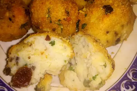 Polpette di merluzzo dorate e croccanti, una metà tagliata rivela un interno morbido con erbe aromatiche e pezzetti scuri.