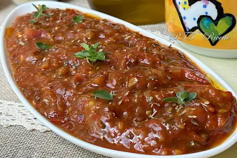 Sugo con pomodorini freschi, profumato con erbe aromatiche, servito in una ciotola bianca.