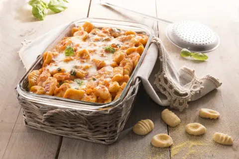Gnocchi di polenta al forno, dorati e filanti, con basilico fresco. Un piatto invitante pronto per essere gustato.