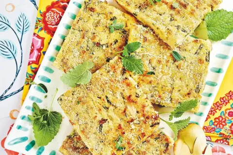 Fette dorate di polpette vegetariane, croccanti fuori e morbide dentro, guarnite con erbe fresche su un piatto decorato.