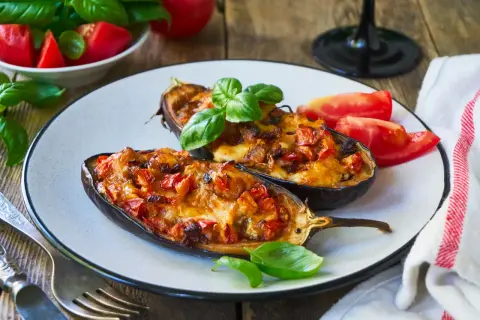 Melanzane ripiene senza carne, dorate e filanti, guarnite con basilico fresco. Un piatto vegetariano invitante.