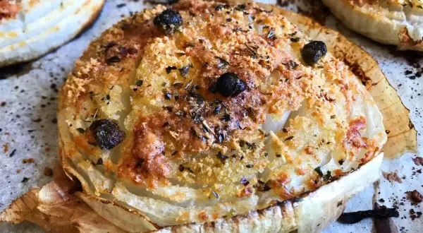Cipolla Giarratana al forno, dorata e croccante, con olive nere e erbe aromatiche.