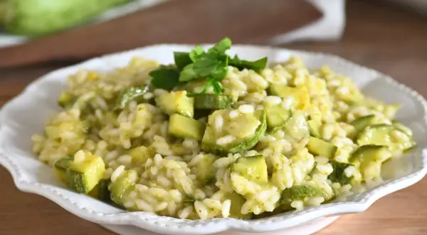 Un cremoso risotto con zucchine, guarnito con prezzemolo fresco, pronto per essere gustato.