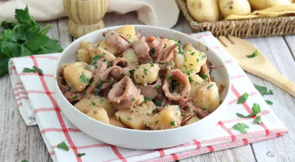 Un gustoso piatto di totani e patate, condito con prezzemolo fresco, pronto per essere gustato.