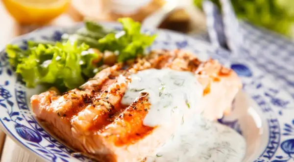 Salmone grigliato con salsa vierge e insalata fresca, un piatto leggero e gustoso.
