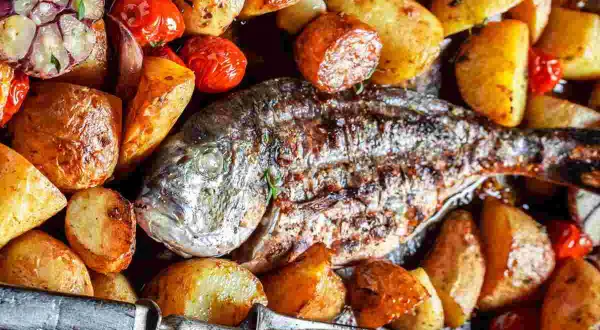 Orata alla ligure al forno, con patate arrosto, pomodorini e aglio. Un piatto succulento e profumato.