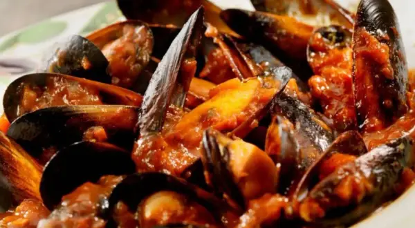 Muscoli alla marinara succulenti, immersi in un sugo rosso ricco e saporito. Un piatto di mare che invita a gustare ogni singolo boccone.