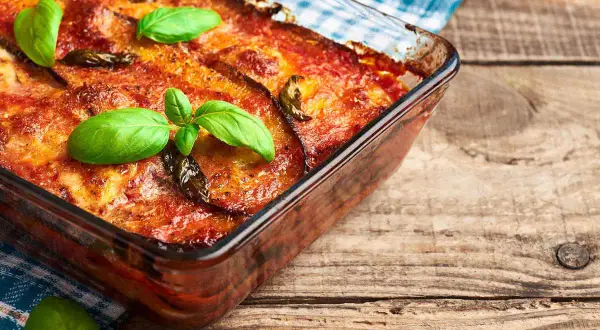 Parmigiana di melanzane in friggitrice ad aria, dorata e profumata, guarnita con basilico fresco. Un piatto gustoso e leggero.