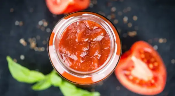 Un vasetto di sugo al pomodoro fatto in casa, con pomodori freschi e basilico, pronto per condire la pasta.