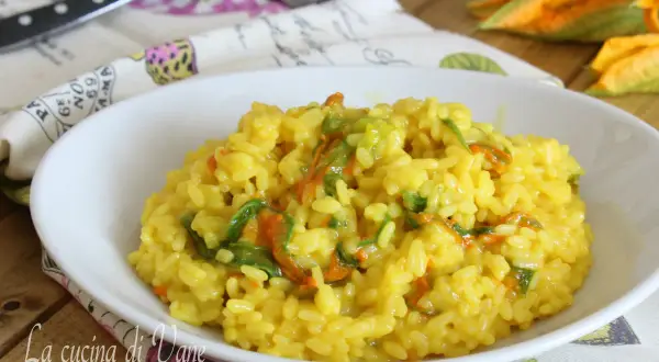Un invitante risotto ai fiori di zucca cremoso, con petali arancioni e verdi che si mescolano al riso giallo dorato.