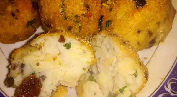 Polpette di merluzzo dorate e croccanti, una metà tagliata rivela un interno morbido con erbe aromatiche e pezzetti scuri.