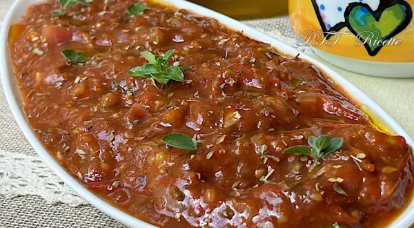 Sugo con pomodorini freschi, profumato con erbe aromatiche, servito in una ciotola bianca.