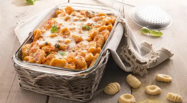Gnocchi di polenta al forno, dorati e filanti, con basilico fresco. Un piatto invitante pronto per essere gustato.